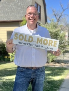Paul Aspelin Grand Junction Listing Agent pictured on a street holding the Sold for More sign rider